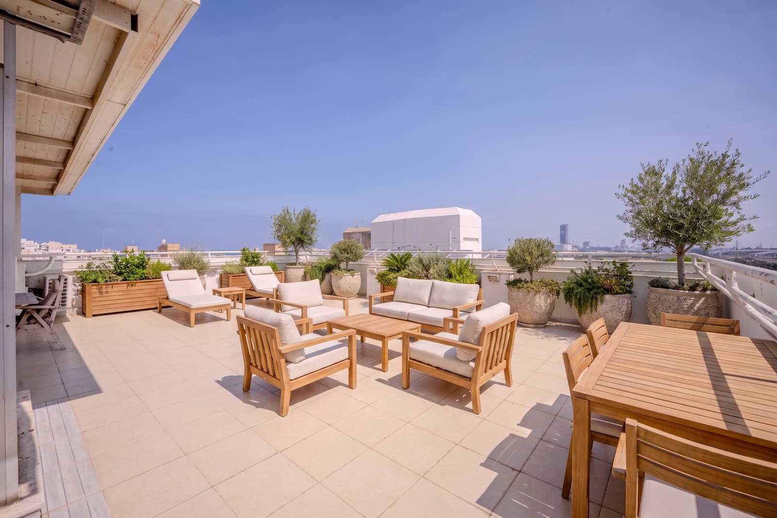 Virtually staged view of the 100 sqm private rooftop with lounge seating, dining and olive trees, the city skyline on the horizon